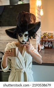 Beautiful Young Woman Prepares For The Carnival And At Home In A White Robe Tries On A White Mysterious Venetian Mask