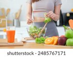 Beautiful young woman preparing a healthy vegetables salad in a kitchen with fresh ingredients. Healthy lifestyle, nutrition and dieting concept.