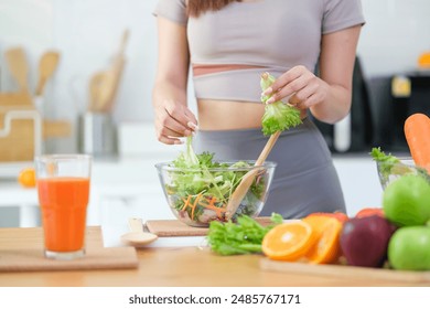 Beautiful young woman preparing a healthy vegetables salad in a kitchen with fresh ingredients. Healthy lifestyle, nutrition and dieting concept.