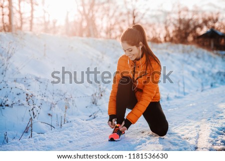Beautiful young woman preparing for training. Snowy mountain morning fitness.