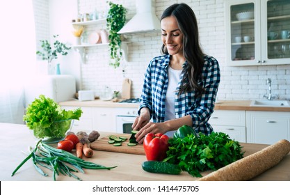 Beautiful young woman is preparing vegetable salad in the kitchen. Healthy Food. Vegan Salad. Diet. Dieting Concept. Healthy Lifestyle. Cooking At Home. Prepare Food. Cutting ingredients on table - Powered by Shutterstock