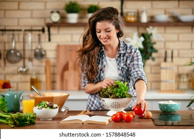 Beautiful young woman is preparing vegetable salad in the kitchen. Healthy Food. Vegan Salad. Diet. Dieting Concept. Healthy Lifestyle. Cooking At Home.