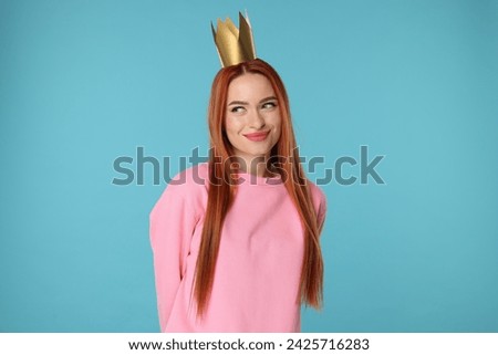 Beautiful young woman with princess crown on light blue background