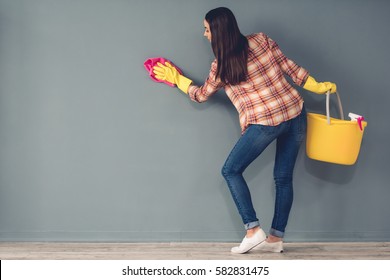 Beautiful Young Woman In Protective Gloves Is Cleaning A Wall