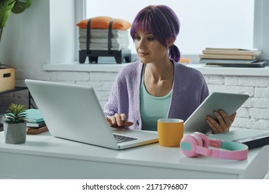 Beautiful Young Woman With Purple Hair Working On Laptop While Sitting At Her Working Place