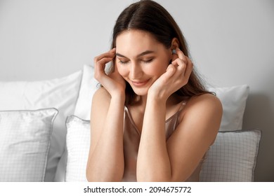 Beautiful Young Woman Putting Ear Plugs Before Sleep In Bedroom