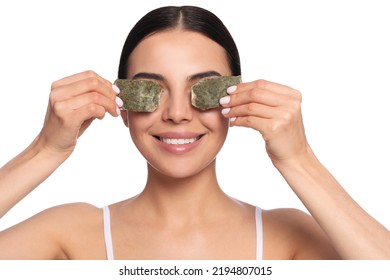 Mujer joven hermosa poniendo bolsas de té verdes en los ojos contra fondo blanco