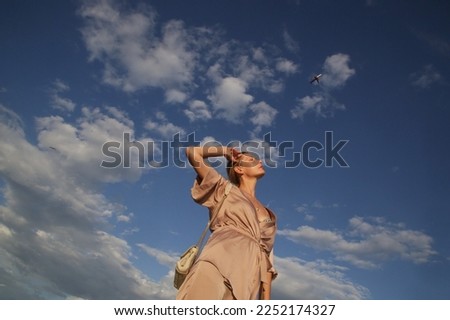 Beautiful young woman raising arms under blue sky, concept of freedom, hapiness and joy