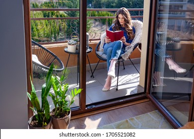 Beautiful Young Woman Reading A Book On The Balcony 