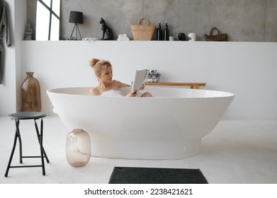 Beautiful young woman reading book or fashion magazine in bathtub - Powered by Shutterstock