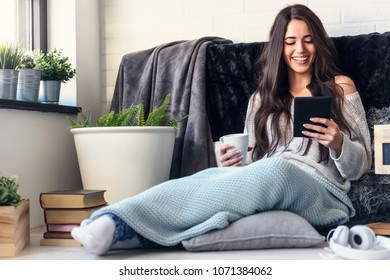 Beautiful Young Woman Reading E Book Reader At Home Surrounded By Books