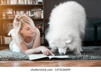 Beautiful Young Woman Reading Magazine With Samoyed Dog