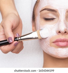 Beautiful young woman receiving facial mask at beauty salon