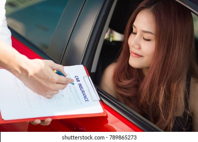Beautiful young woman in red car is talking to car insurance salesman. Car insurance concept.