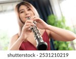 Beautiful young woman in a red dress playing the clarinet 
,Classical musician oboe playing.