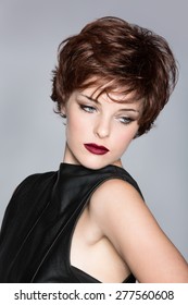 beautiful young woman with red hair wearing short pixie crop hairstyle on studio background