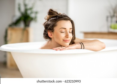 Beautiful young woman relaxing lying in the bathtube in the bathroom