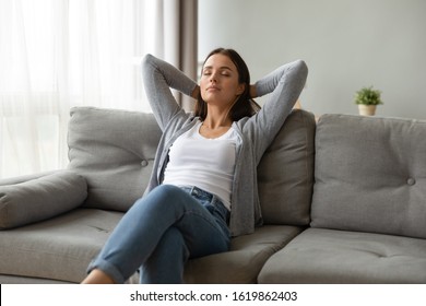 Beautiful young woman relaxing on comfortable couch at home, sitting with hands behind head, stretching, pretty girl with closed eyes resting sleeping on sofa in modern living room, meditating - Shutterstock ID 1619862403