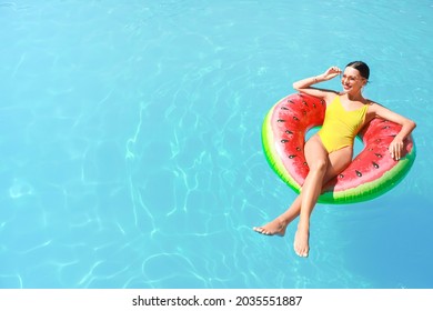 Beautiful young woman relaxing on swimming ring in pool