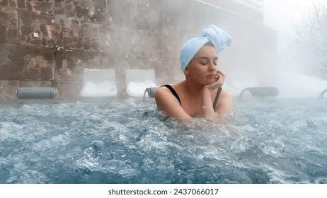 Beautiful young woman relaxing in outdoor hot thermal pool. Snowy winter day. Thick steam. Enjoying Spa on holidays. High quality photo - Powered by Shutterstock