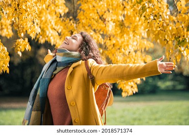 Beautiful young woman relaxing at park during autumn season with closed eyes. Happy free natural girl breathing deeply in park with foliage in background. Pretty woman expressing freedom outdoor. - Shutterstock ID 2018571374