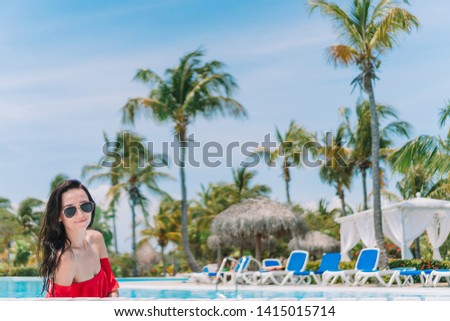 Beautiful young woman relaxing in swimming pool. Girl in red bikini in outdoor pool at luxury hotel