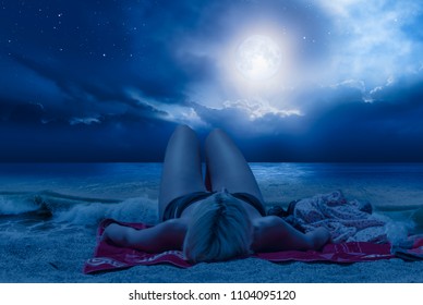 Beautiful young woman resting on beach in summer at night