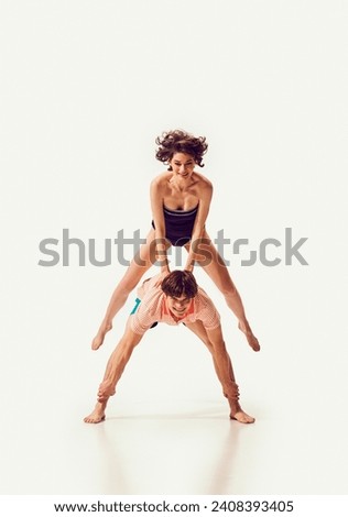 Beautiful young woman in rets swimsuit jumping over man's back, friends playing together against white background. Concept of summer vacation, travelling, retro style, fashion, leisure time, holiday Stok fotoğraf © 