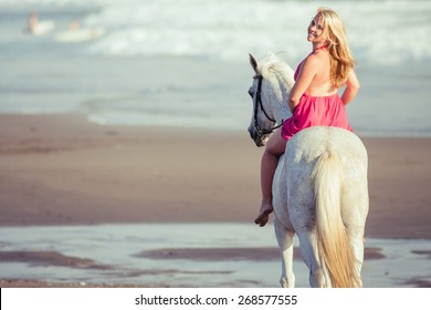 Beautiful young woman riding a horse along the beach, she is happy of her hobby