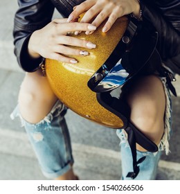 Beautiful Young Woman In Rock Black Style Leather Jacket With Glitter Gold Motorbike Helmet And White Paper Tea Or To Go Coffee Cup. Hipster Urban Style Girl. Lifestyle Outdoor City Portrait.