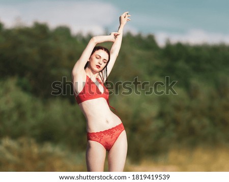 Beautiful young woman with scarlet dreadlocks and red bathing suit enjoying nature. 