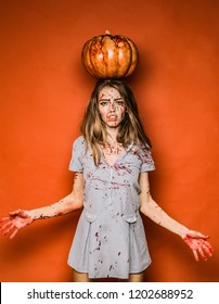 Beautiful Young woman as sexy vampire in blue dress - halloween concept. Scary bloody zombie girl with pumpkin. Woman with red blood and with blond hair. Halloween party art design
