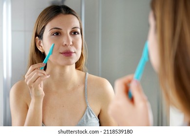 Beautiful young woman shaving her face by razor at home. Pretty woman using razor on bathroom. - Shutterstock ID 2118539180