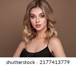 A beautiful young woman with shiny wavy blonde hair. Model with healthy skin, close up portrait. Cosmetology, beauty and spa