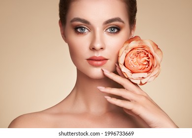 A Beautiful Young Woman With Shiny Wavy Blonde Hair. Girl With A Rose Flower. Model With Healthy Skin. Cosmetology, Beauty And Spa