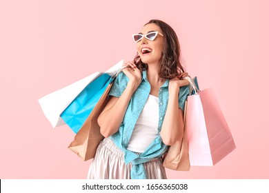 Beautiful young woman with shopping bags on color background - Powered by Shutterstock