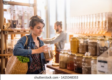 Beautiful Young Woman Shopping In A Bulk Food Store. She Buys Organic Spices In Jars