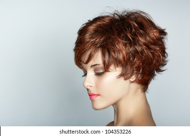 beautiful young woman with short brown haircut wears pink lipstick on studio background with copy space.