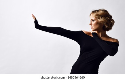 Beautiful Young Woman With Short Curly Blonde Hair In Stylish Black Off Shoulder Extra Long Sleeve Tight Dress Posing On White Background 