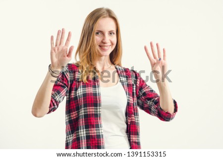 Beautiful young woman shows nine fingers while standing on a light background. Number 9 - concept.