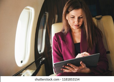 beautiful young woman sits in a plane and works on laptop - Powered by Shutterstock