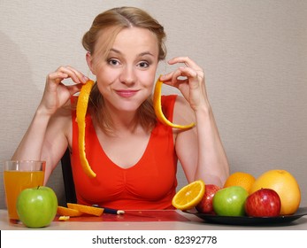 The beautiful young woman sits at a table and eats fruit