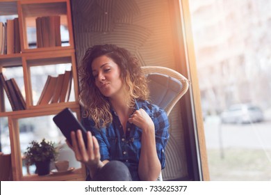 Beautiful young woman sitting in a cafe taking a selfie - Shutterstock ID 733625377