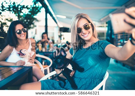 Beautiful young woman sitting in cafe with her adorable French bulldog puppy. Spring or summer city outdoors. People with dogs 