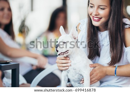 Beautiful young woman sitting in cafe with her adorable French bulldog puppy. People with dogs theme.