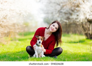 beautiful young woman sitting in front of wonderful blooming trees with her dog