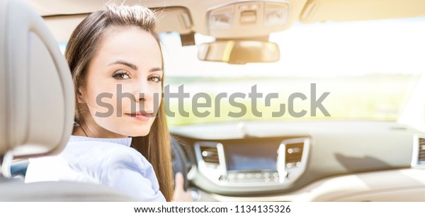 Beautiful young woman sitting in\
the interior of a new car with a smile. He is glad he is a\
driver.