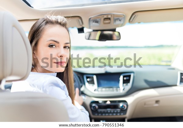 Beautiful young woman sitting in\
the interior of a new car with a smile. He is glad he is a\
driver.