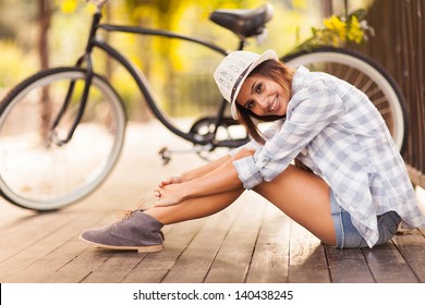 beautiful young woman sitting next to her bike outdoors