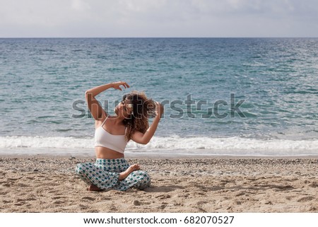 Beautiful young woman sitting on the beach and arranging her hair